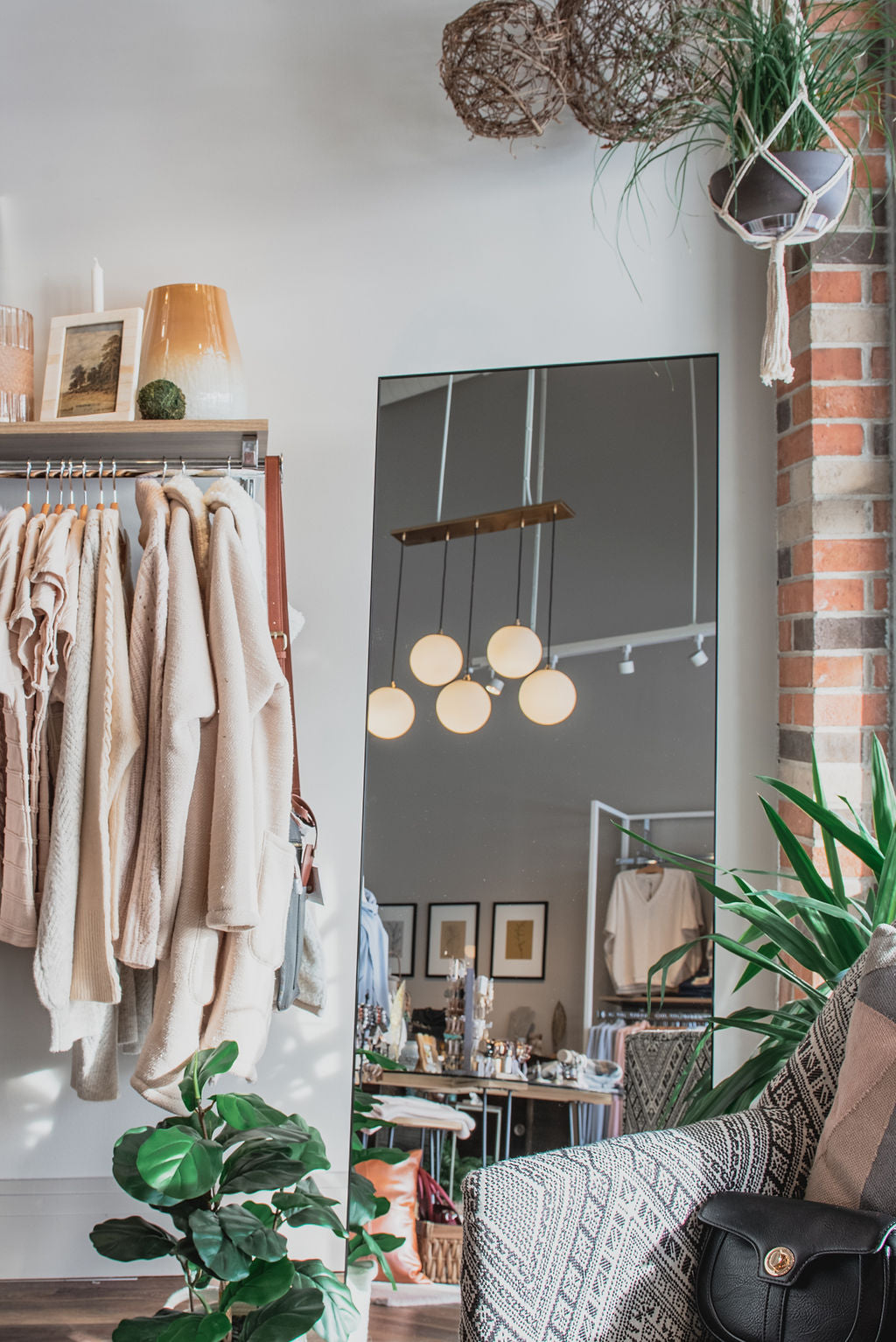 Interior image of Tru Blue Boutique with clothing hanging on bar and shelf with purses, artwork and home accessories and decor.