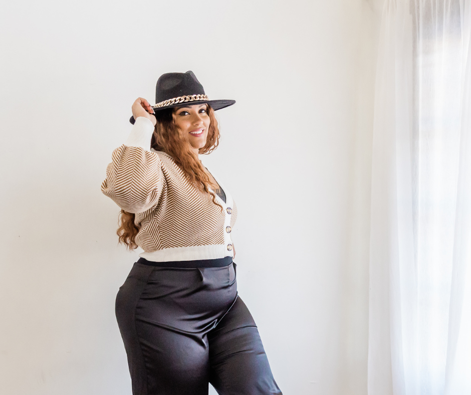 Curvey woman wearing fashion vegan leather pants and hat.